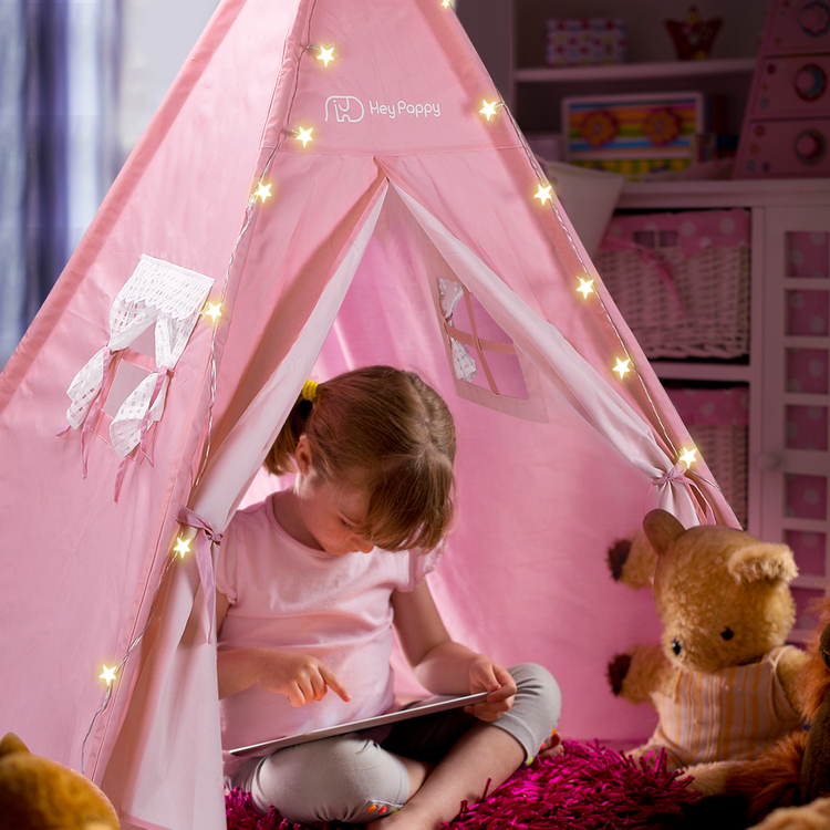 Little girl reading inside the pink tent