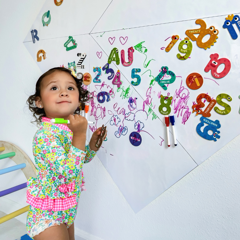 Little girl using magnetic board to doodle