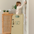 Little boy using Beige Heypappy Toddler Helper Tower to hang the frame on the wall