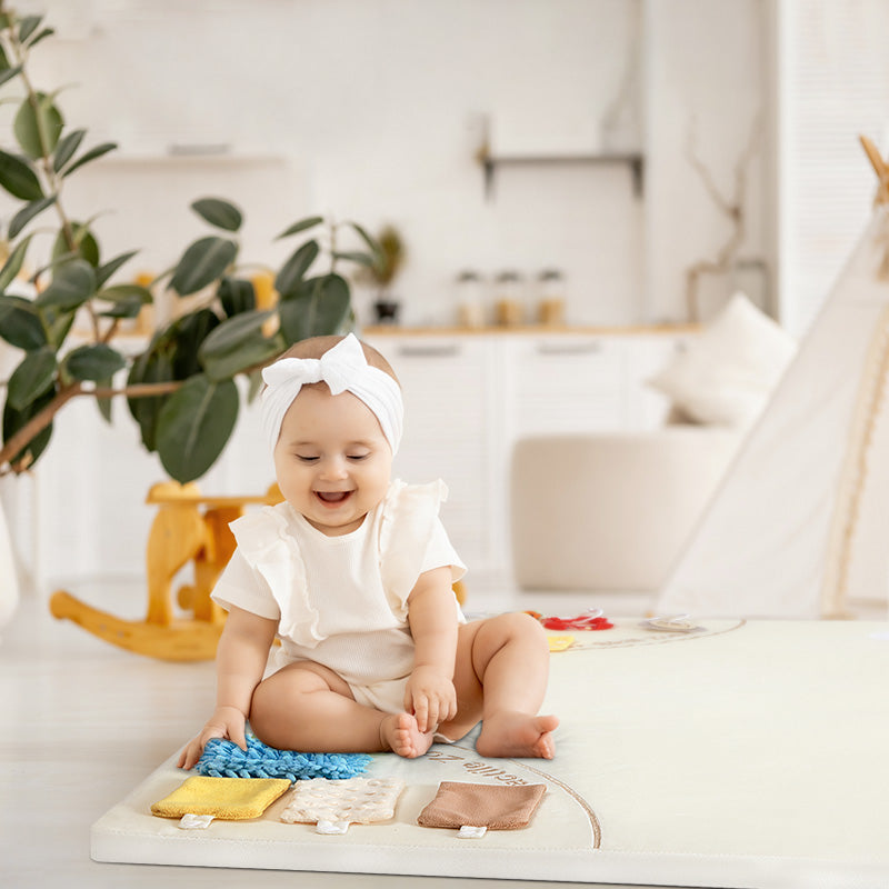 Baby sitting on the beige sensory mat