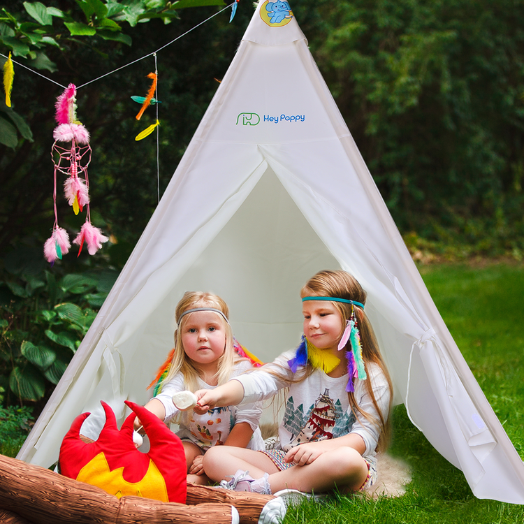 Two boys set up a white tent in the grass.