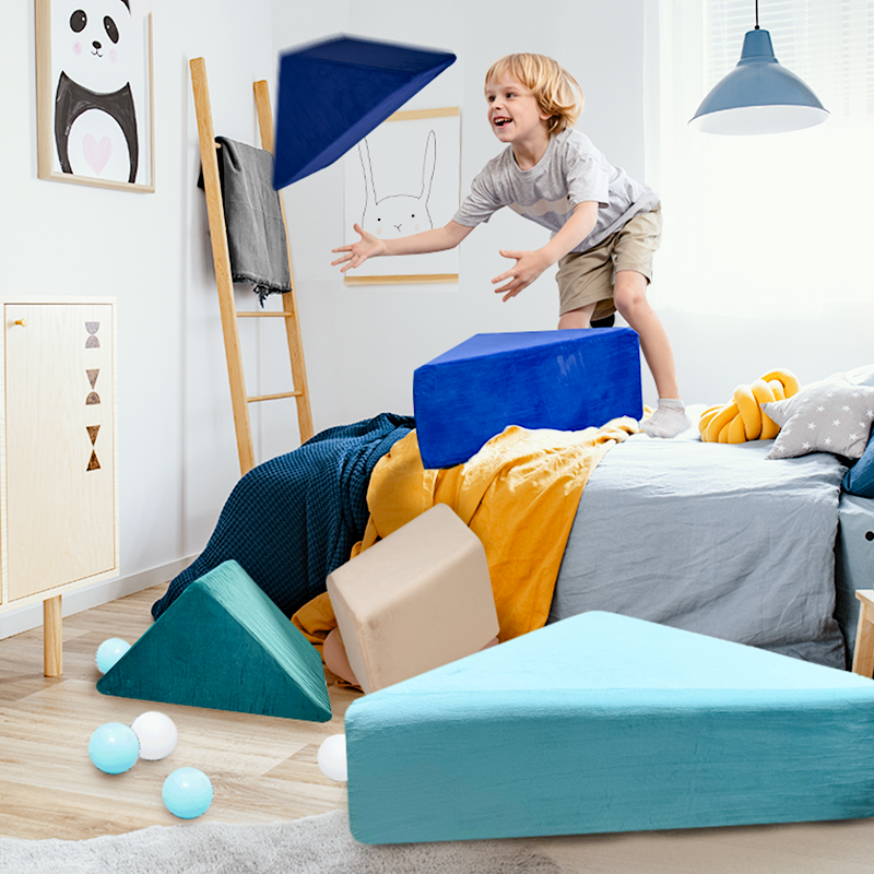 A young boy throws pieces of the Tangram play couch in a bedroom filled with playful decor.