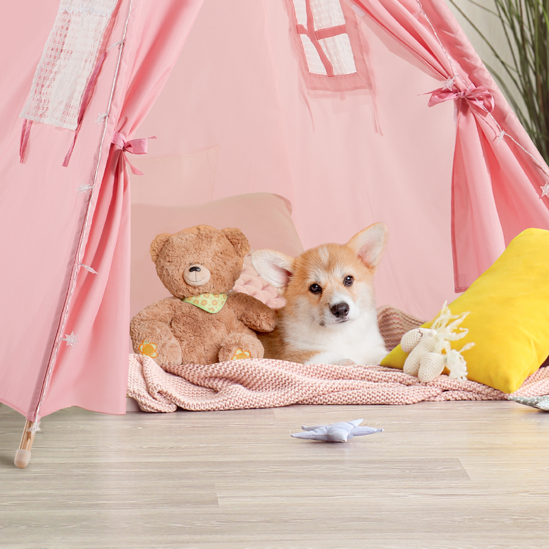 A small dog and a teddy bear are inside a pink kids' tent.