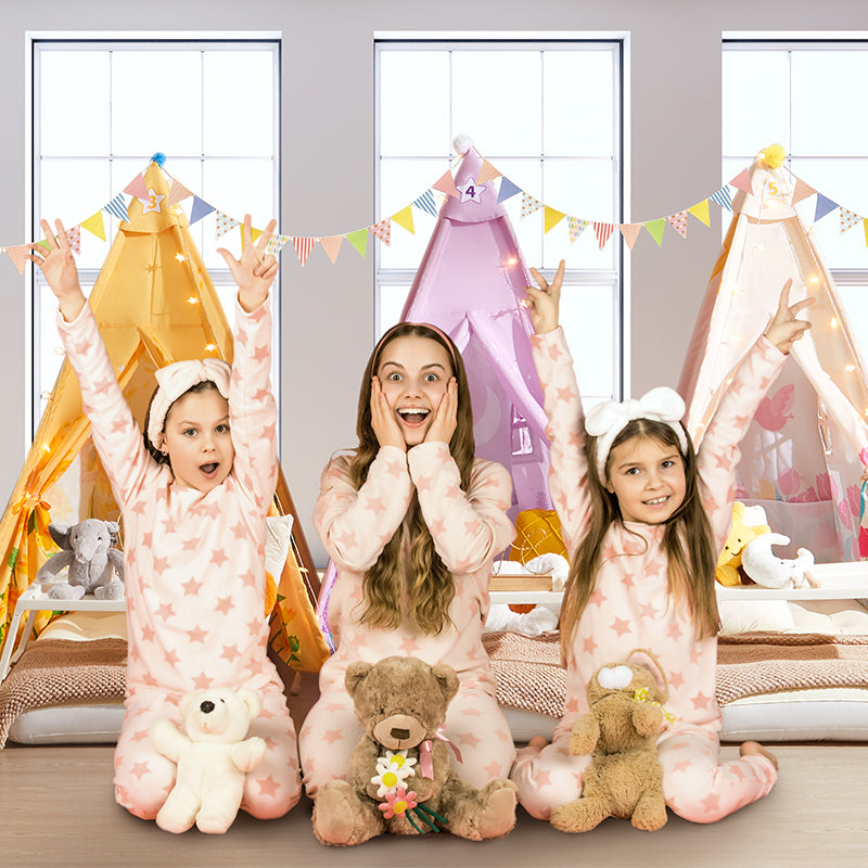 Three little girls sitting in front of three colorful kid's tents.