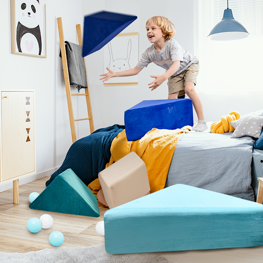A young boy throws pieces of the Tangram play couch in a bedroom filled with playful decor.
